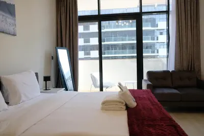 a bedroom with a bed and a chair and a large window at Mira Holiday Homes - Cozy studio in Meydan in Dubai