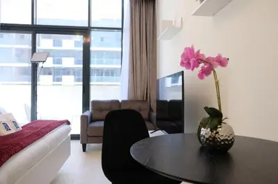 a living room with a table with a vase with a flower on it at Mira Holiday Homes - Cozy studio in Meydan in Dubai