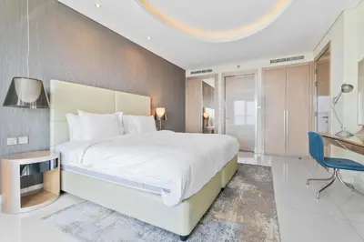 a bedroom with a large white bed and a desk at ALiving Elite 2BR I Burj Khalifa View I Paramount Towers, 6102 in Dubai
