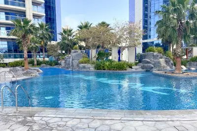 a large swimming pool in a city with palm trees at ALiving Elite 2BR I Burj Khalifa View I Paramount Towers, 6102 in Dubai
