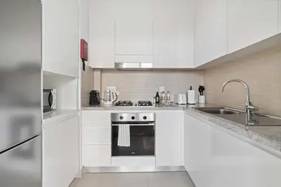 a white kitchen with a sink and a stove at Silkhaus modern 1BDR in Downtown with balcony, pool, gym in Dubai