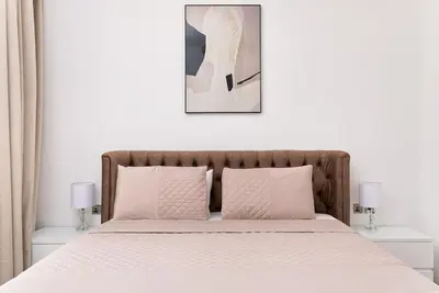 a bedroom with a bed with white sheets and a picture at New apt in Dubai Marina with balcony and sea view in Dubai