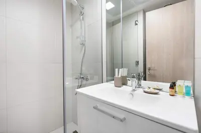 a white bathroom with a sink and a shower at Silkhaus new furnished studio in JVC, Luma 21 in Dubai