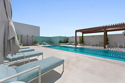 a swimming pool with blue chaise lounge chairs next to a building at Silkhaus new furnished studio in JVC, Luma 21 in Dubai