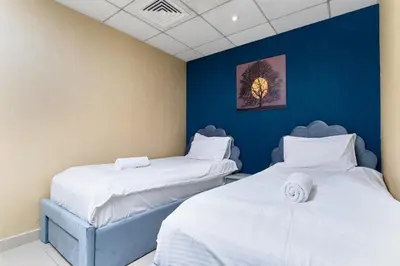 two beds in a room with blue walls at Bellavista - Striking - 1BR with Extra Twin Room - 29 boulevard - Partial Fountain View in Dubai