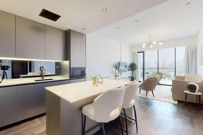 a kitchen with white chairs and a kitchen island with a counter top at O Ten, Al Jaddaf - Smart One Bedroom in Dubai