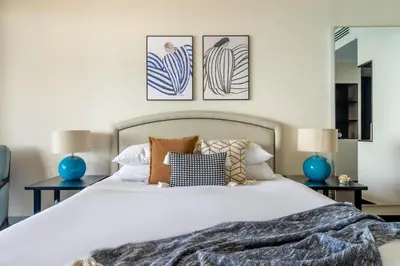 a bedroom with a large white bed with blue lamps at GuestReady - Posh Living with Burj Al Arab view in Dubai