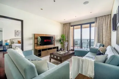 a living room with blue couches and a television at GuestReady - Burj Al Arab view at Royal Amwaj in Dubai