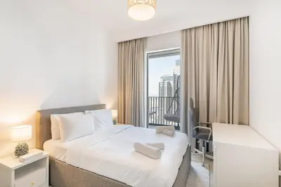 a bedroom with a bed and a desk and a window at Spacious 2 Bedroom on High Floor in Creek Horizon - Allsopp&Allsopp in Dubai