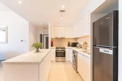 a kitchen with white cabinets and a stainless steel refrigerator at Spacious 2 Bedroom on High Floor in Creek Horizon - Allsopp&Allsopp in Dubai