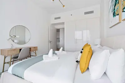 a white bedroom with a white bed and a mirror at Silkhaus furnished 1BDR in Downtown new tower in Dubai