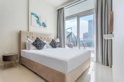 a bedroom with a large bed and a large window at Reva Residences - One Bedroom Apartment by the S Holiday Homes in Dubai