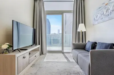 a living room with a tv and a large window at Reva Residences - One Bedroom Apartment by the S Holiday Homes in Dubai