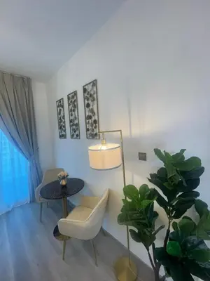 a living room with a table and a chair and a plant at Diamond Tower Marina Apartment in Dubai