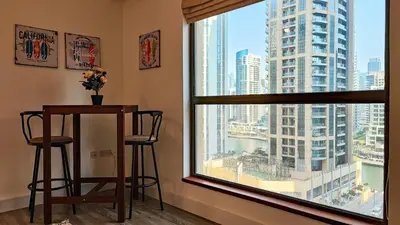 a room with a window with a table and two stools at La Buena Vida Holiday Homes - Deluxe, very spacious 5 Bedroom plus maidroom in Best location of JBR, Near to Beach, Marina and Tram station in Dubai