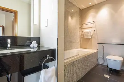 a bathroom with a sink and a toilet and a tub at Nasma Luxury Stays - Central Park Tower in Dubai