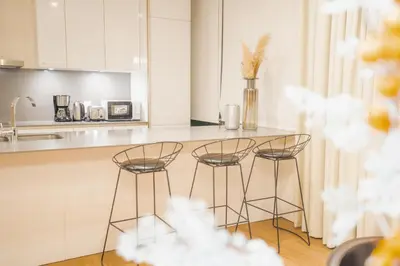 a kitchen with three bar stools and a counter at Nasma Luxury Stays - City Walk Building 5 in Dubai