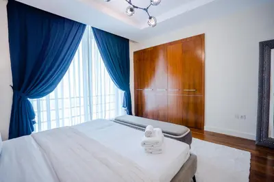 a bedroom with a bed with blue curtains and a large window at Nasma Luxury Stays - Limestone House in Dubai