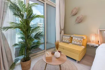a living room with a couch and a palm tree at Cosy & Chic Studio One Marina with balcony & View in Dubai