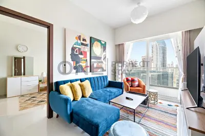 a living room with a blue couch and a large window at In the heart of Business Bay - Bills included in Dubai