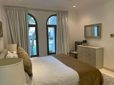 a bedroom with a bed and a dresser and windows at Palm Jumeirah Beachfront private pool villa 5 BR & 1 maids room with access to beach in Dubai