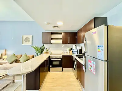 a kitchen with a stainless steel refrigerator and a couch at Cosmos Living Dubai Arch Tower Pool, Gym & Balcony in Dubai