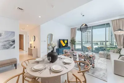 a dining room and living room with a table and chairs at Vogue Creek Harbour The Grand Waterfront Living close to Downtown, Burj Khalifa and Dubai Mall, Two Bedroom Apartment with Balcony, Canal and Vibrant Community View, Access to all Amenities in Dubai