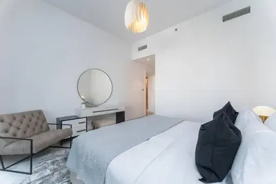 a white bedroom with a bed and a mirror at Vogue Creek Harbour The Grand Waterfront Living close to Downtown, Burj Khalifa and Dubai Mall, Two Bedroom Apartment with Balcony, Canal and Vibrant Community View, Access to all Amenities in Dubai