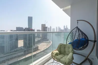 a chair on a balcony with a view of a city at Gala Guests - Maison Prive Canal View Collection in Dubai