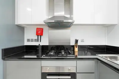 a kitchen with white cabinets and a stove top oven at Gala Guests - Maison Prive Canal View Collection in Dubai