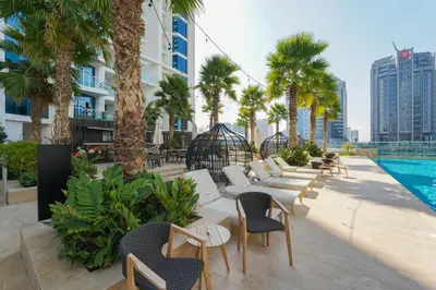 a hotel patio with palm trees and a swimming pool at ALiving Stylish Studio with Partial Burj & Canal Views- Prive , Business bay 713 in Dubai