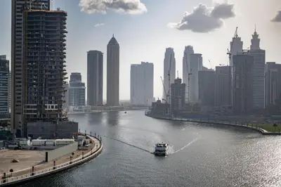 a boat traveling down a river in a city at ALiving Stylish Studio with Partial Burj & Canal Views- Prive , Business bay 713 in Dubai