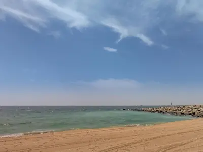 a beach with the ocean and a rocky pier at Amazing 1BD sea view apartment in Port de La Mer in Dubai