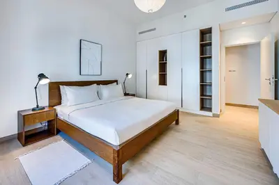a bedroom with a large bed with a night stand and a table at Amazing 1BD sea view apartment in Port de La Mer in Dubai