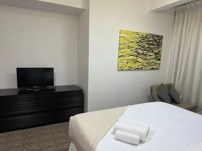 a bedroom with a white bed and a television at ModernLux - Luxury Duplex 1 BR in Movenpick Hotel JLT with Lake View in Dubai