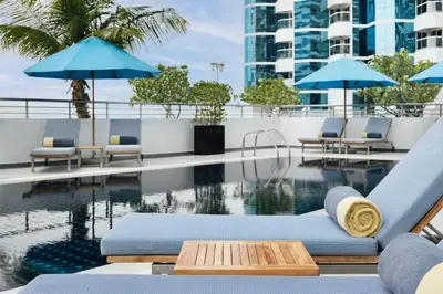 a pool with chairs and umbrellas on a building at ModernLux - Luxury Duplex 1 BR in Movenpick Hotel JLT with Lake View in Dubai