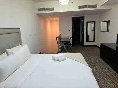 a bedroom with a large white bed and a chair at ModernLux - Luxury Duplex 1 BR in Movenpick Hotel JLT with Lake View in Dubai