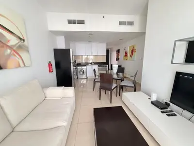 a living room with a white couch and a kitchen at ModernLux - Luxury Duplex 1 BR in Movenpick Hotel JLT with Lake View in Dubai