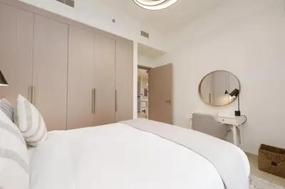 a white bedroom with a large bed and a mirror at Maison Privee - Luxury 2Bedroom with Burj Khalifa & Fountain Views in Dubai