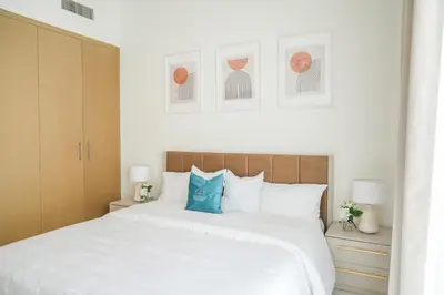 a bedroom with a large white bed with blue pillows at Elegant Apartment With Balcony Amidst Vibrant Area in Dubai