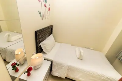 a small bedroom with a white bed and a mirror at Roomy Dubai Hostel Small Rooms and Partitions at Marina in Dubai