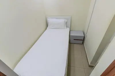 a small room with a white bed and a trash can at Roomy Dubai Hostel Small Rooms and Partitions at Marina in Dubai