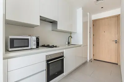 a white kitchen with a microwave and a stove at Frank Porter - Marquise Square Tower in Dubai