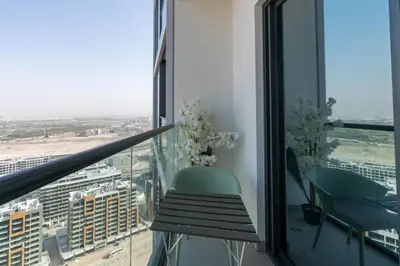 a balcony with a green chair and a view of a city at Modern 1bdr - 10min from Burj Khalifa - Sobha Waves in Dubai
