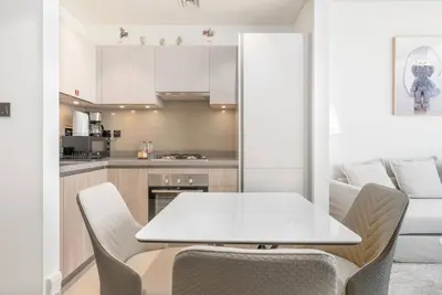 a kitchen with a white table and chairs and a couch at Modern 1bdr - 10min from Burj Khalifa - Sobha Waves in Dubai