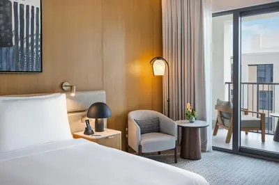 a hotel room with a bed and a chair and a balcony at Vida Creek Beach Hotel in Dubai