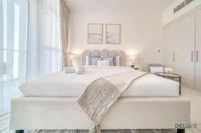 a white bedroom with a large white bed at Opulent Studio at Carson C DAMAC Hills Dubailand by Deluxe Holiday Homes in Dubai