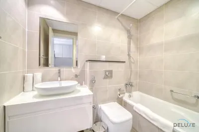 a bathroom with a sink and a toilet and a tub at Opulent Studio at Carson C DAMAC Hills Dubailand by Deluxe Holiday Homes in Dubai