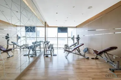 a gym with several treadmills and cardio machines at Opulent Studio at Carson C DAMAC Hills Dubailand by Deluxe Holiday Homes in Dubai