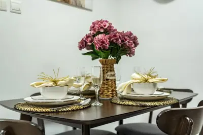 a table with two plates and a vase of flowers at The Smart Concierge - Princess tower in Dubai
